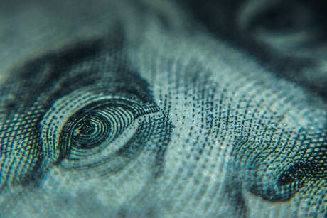 Ein Bild, das eine blau-grüne Grafik mit Auge und Nase zeigt. Es ist eine Detailaufnahme eines 100-Dollar-Scheins.