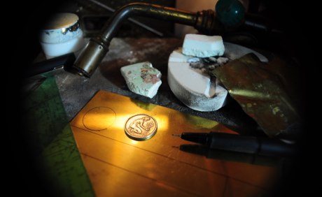 Eine Werkbank mit Schweißbrenner, Lötkolben und einer goldenen Münze