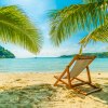 Ausblick vom Strand auf ein blaues Meer, im Sand steht ein hölzerner Stuhl