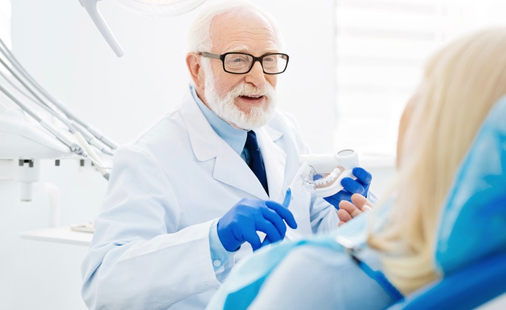 Ein älterer Zahnarzt behandelt eine ältere Patientin.  