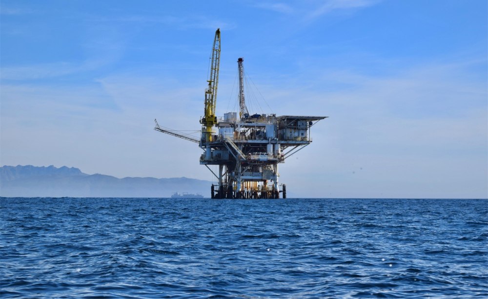 Off-Shore Anlage im Meer mit Schiff und Bergen im Hintergrund