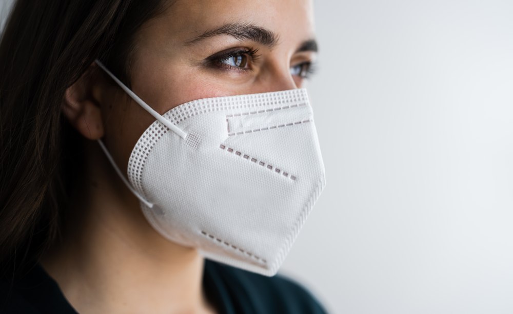 Arbeitgeber sind aber weiterhin verpflichtet zu beurteilen, welche Gefährdung in ihrem Betrieb von dem Virus ausgeht. Ein Bild, das das Gesicxht einer Frau mit FFP2-Maske im Dreiviertel-Profil zeigt