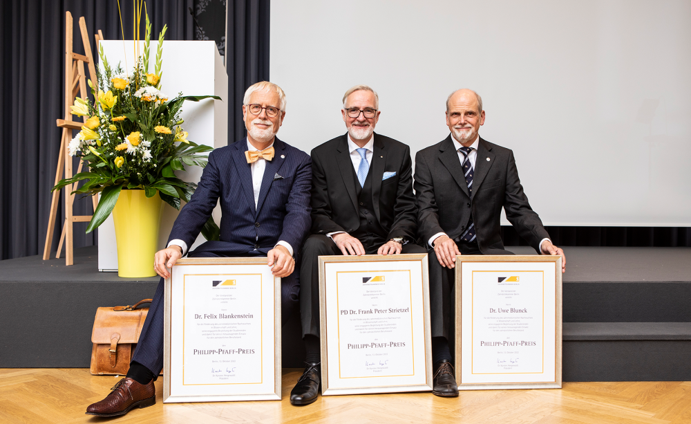 Philipp-Pfaff-Preis 2022 vergeben Drei Männer sitzend auf Podium hinter Urkunden des Philipp-Pfaff-Preises