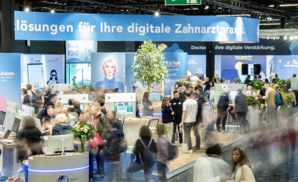 Messestand von CGM mit vielen Besuchern, die teilweise nur verschwommen erkennbar sind