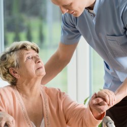 Ein Pfleger hilft einer Seniorin.  
