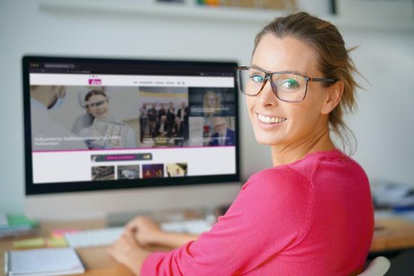 Fröhliche Frau vor iMac mit dzw.de auf dem Bildschirm