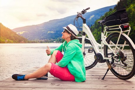 Frau sitz am See mit E-Bike