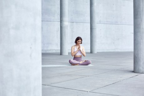 Junge Frau im Yogasitz auf einem öffentlichen Platz