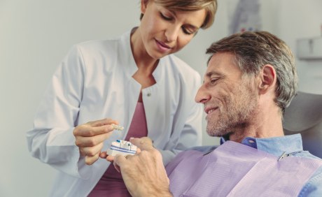 Zahnärztin zeigt Patient Brücke