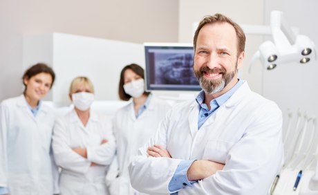 Gruppenfoto von Zahnarzt mit Team im Behandlungsraum