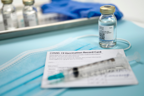 Nahaufnahme Covid-Impfstoffphiole mit Spritze, Maske und Card