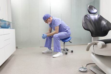 Zahnarzt alleine zusammengesunken auf Stuhl im leeren Behandlungszimmer