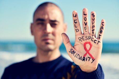 Nahaufnahme einer Hand mit aufgemalter AIDS-Schleife und positiven Worten