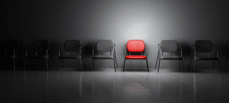 Reihe von schwarzen, leeren Stühlen mit einem roten Stuhl in der Mitte