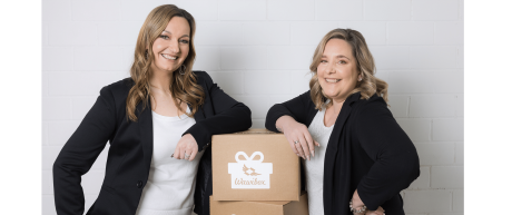 Zwei lächelnde Frauen neben großen Pappboxen von Wawibox