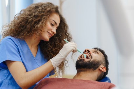 Zahnärztin sieht sich Zähne eines männlichen Patienten an
