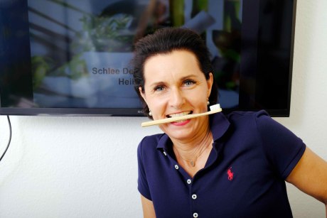 Birgit Schlee hält mit den Zähnen einer Bambuszahnbürste quer fest