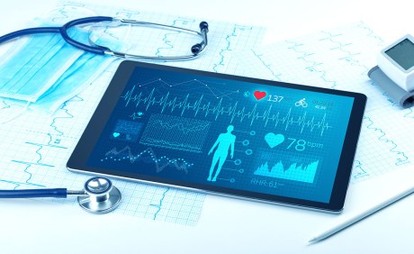 Bild eines Stethoskops, ausgedruckte EKG-Kurven, eines Blutdruckmessgeräts und eines Tablets mit einer medizinischen App