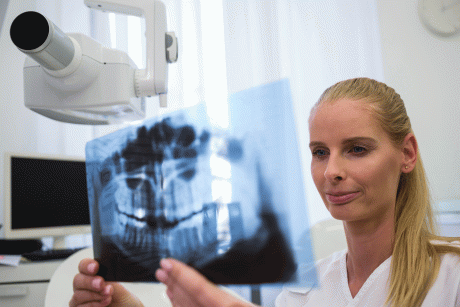 Frau betrachtet Röntgenaufnahme eines Kiefers