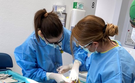 zwei Frauen mit Lupenbrillen und Schutzkittel bei einer OP