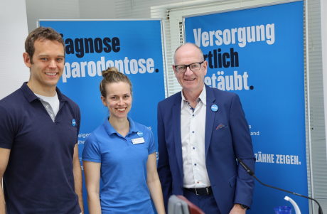Drei vorrangig blau gekleidete Menschen im Halbprotrait für die Kampagne Zähne zeigen