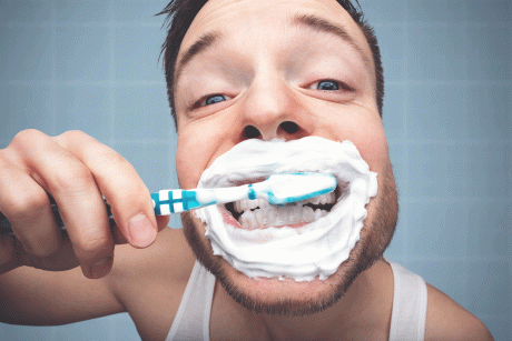 Mann mit Zahnbürste und Schaum um den Mund