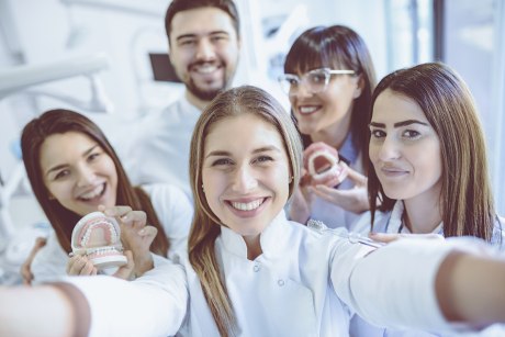 vier Frauen und ein Mann in weißen Kitteln mit Zahnarzt-Utensilien