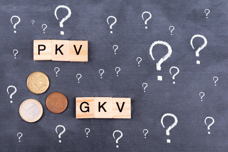 Holzbuchstaben die PKV und GKV ergeben und Fragezeichen auf Kreidetafel