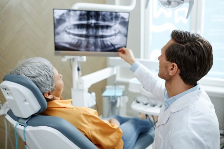 Senior citizen listening to orthodontist explanation of human teeth