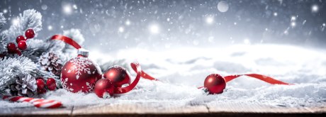 Ein Bild, das rote Weihnachtskugeln im Schnee zeigt