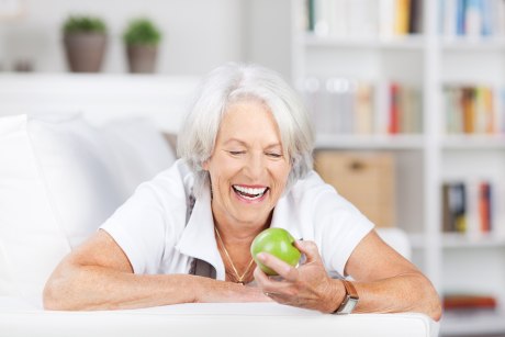 ältere Frau, Apfel in der Hand, lacht