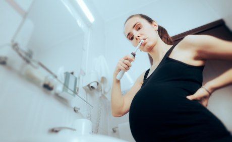 Schwangere Frau putzt sich die Zähne
