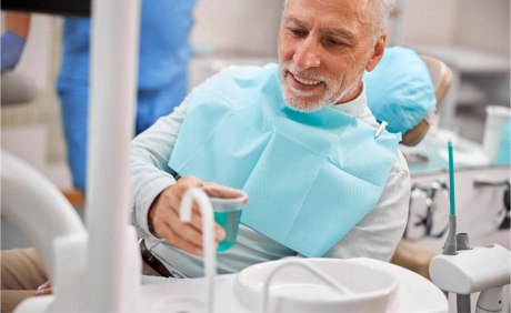 Mann spült Mund beim Zahnarzt