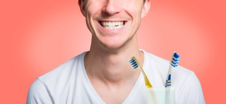 Ein Mann hält zwei Zahnbürsten in die Kamera