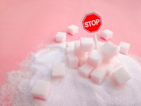 Würfelzucker in Zuckerhaufen, in dem ein Stop-Schild steckt