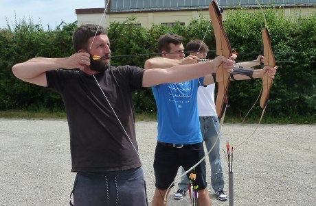 drei Männer stehen nebeneinander mit gespannten Bögen