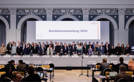 Zwei lange Reihen von Menschen hinter einem Präsidium Aufschrift Bundesversammlung 2024 im Hintergrund