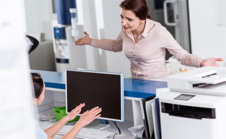 Frau gestikulierend vor Empfangstresen einer Arztpraxis