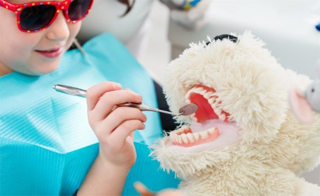 Junge auf Zahnarztstuhl untersucht Handpuppe mit Handspiegel