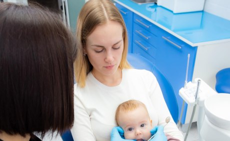 Kleinkund auf dem Schoß der Mutter auf dem Zahnarztstuhl