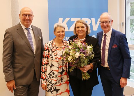 zwei Männer und zwei Frauen stehen nebeneinander vor einem KZBV-Schild