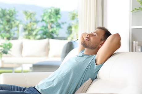Mann halb liegend auf Sofa mit entspannt geschlossenen Augen