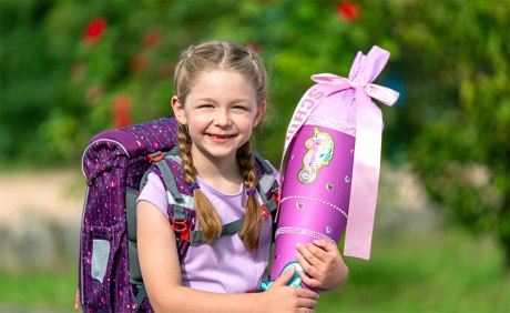 Schulanfängerin mit Ranzen und Schultüte in Lila/Pink