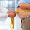 Arzt misst Bauchumfang eines dicken Mannes