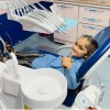 Kind zeigt Daumen hoch auf einer Zahnarzt-Behandlungseinheit