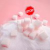 Würfelzucker in Zuckerhaufen, in dem ein Stop-Schild steckt