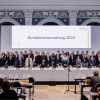 Zwei lange Reihen von Menschen hinter einem Präsidium Aufschrift Bundesversammlung 2024 im Hintergrund