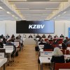 Heller Saal mit Menschen in parlamentarischer Bestuhlung mit Leinwand KZBV-Schriftzug