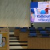 Frau spricht an Pult, im Hintergrund große Präsentationsleinwand