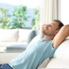 Mann halb liegend auf Sofa mit entspannt geschlossenen Augen